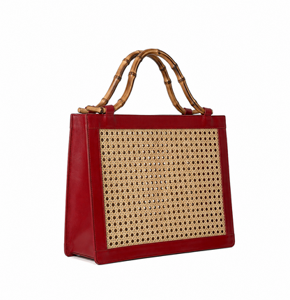 A red leather tote bag featuring a large woven cane panel on the front and natural bamboo handles, shown against a plain white background.