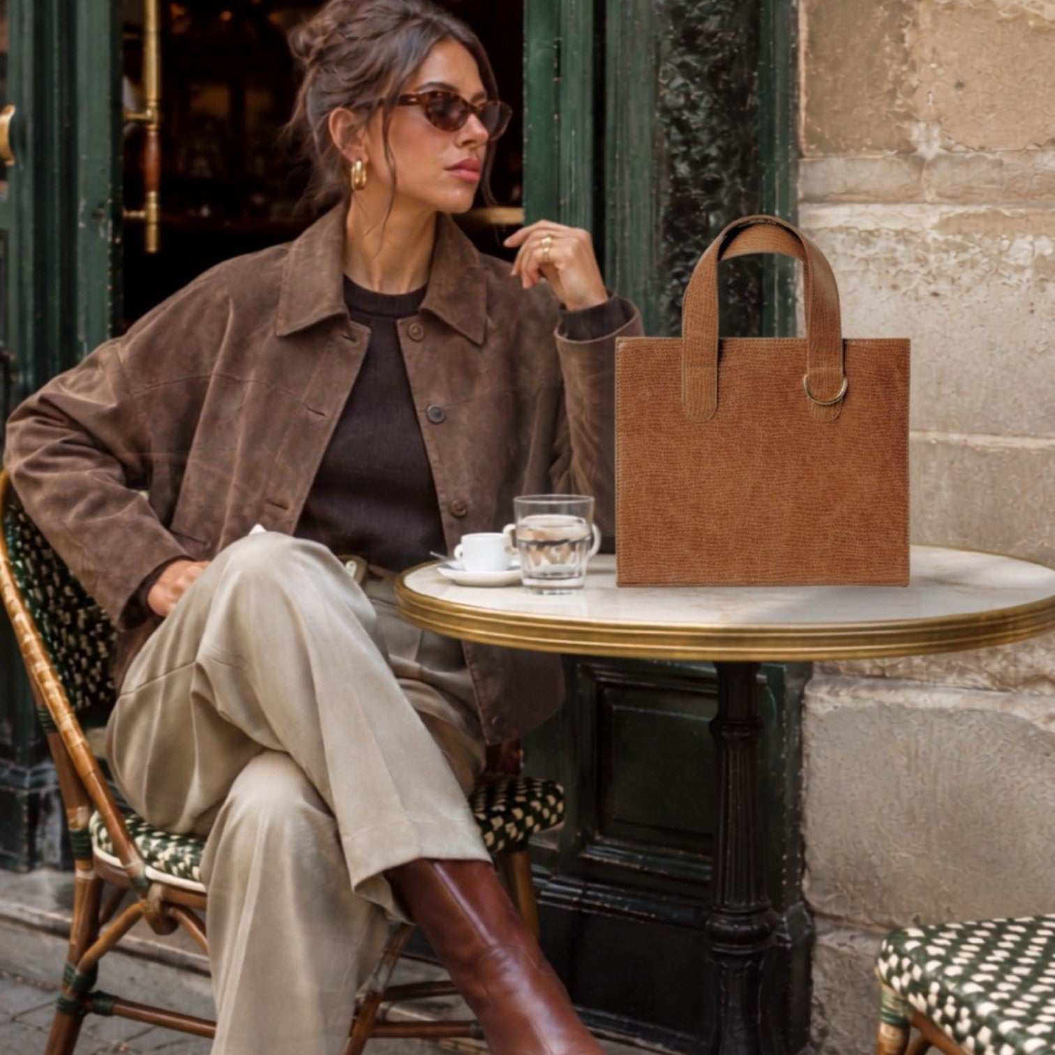 Shop Sarah Stewart Claire Maxi brown embossed goatskin leather tote bag with gold hardware on a cafe table