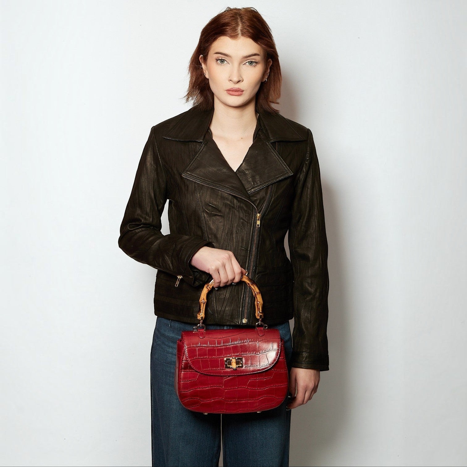 Shop Sarah Stewart Chloe handbag in red embossed goat skin suede with bamboo handle and gold closure held by a model