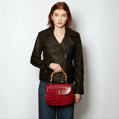 Shop Sarah Stewart Chloe handbag in red embossed goat skin suede with bamboo handle and gold closure held by a model