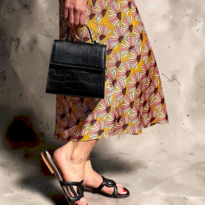 Shop Sarah Stewart The Robin black goat skin leather handbag with crocodile pattern and gold hardware held by a model